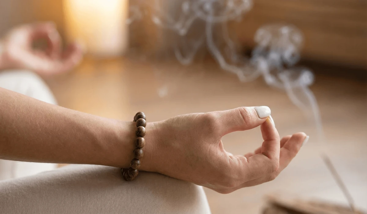 The Spiritual Significance and Healing Benefits of Wearing Agarwood Beads 3 - Buddha Bodhis A person wearing an Agarwood bracelet on the left hand for mindfulness and emotional grounding during meditation.