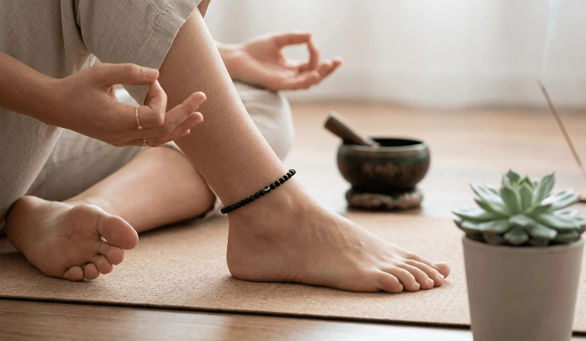 The Spiritual Benefits and Healing Properties of Wearing a Black Obsidian Anklet 2 - Buddha Bodhis A woman wearing a black obsidian anklet on her left leg during meditation for protection and emotional stability.