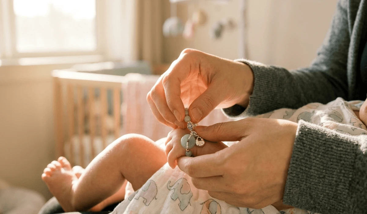 The Spiritual Meaning and Symbolism of a Baby’s Bracelet Breaking 3 - Buddha Bodhis A parent's hand placing a protective jade bracelet on a baby's left wrist to establish a spiritual boundary and energy shielding.