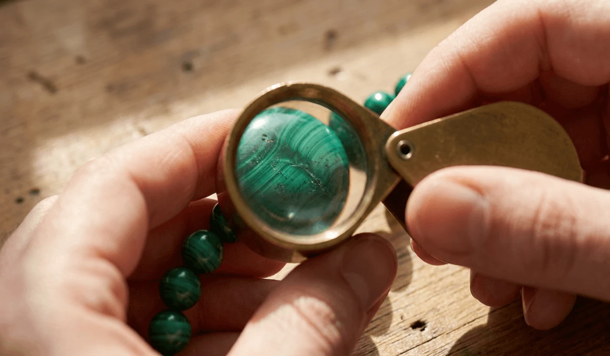 How to Tell If Your Gemstone Mala Is Real: A Guide to Spotting Glass and Plastic Beads - Buddha Bodhis Inspecting authentic gemstone mala beads with a jeweler loupe to check natural inclusions and stone quality.