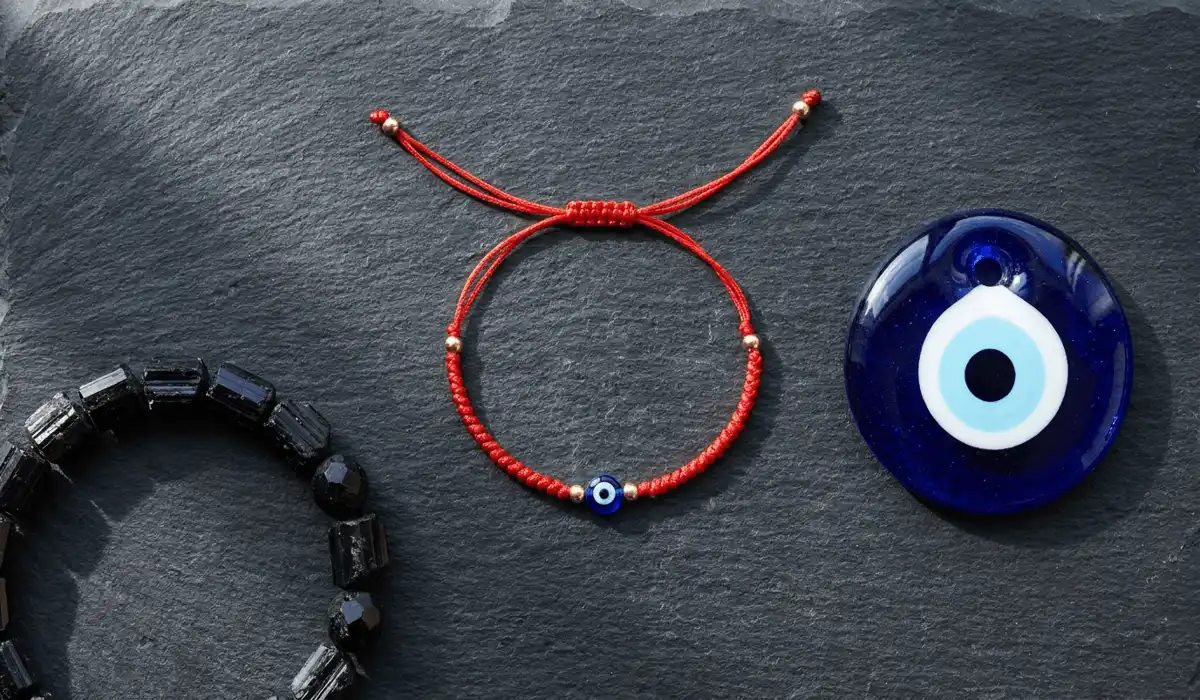 How to Tie and Bless a Red String Bracelet for Protection: A Step-by-Step Ritual Guide 5 - Buddha Bodhis Flat lay showcasing a red string protection bracelet next to a Black Tourmaline bracelet and glass Evil Eye amulet.
