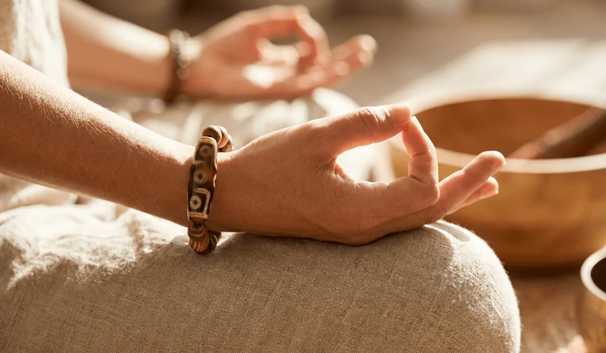 21-Eye Dzi Bead Meaning: Spiritual Benefits and Symbolism 6 - Buddha Bodhis Close-up of a person wearing a 21 eye dzi bead bracelet on the left wrist during a mindfulness meditation session