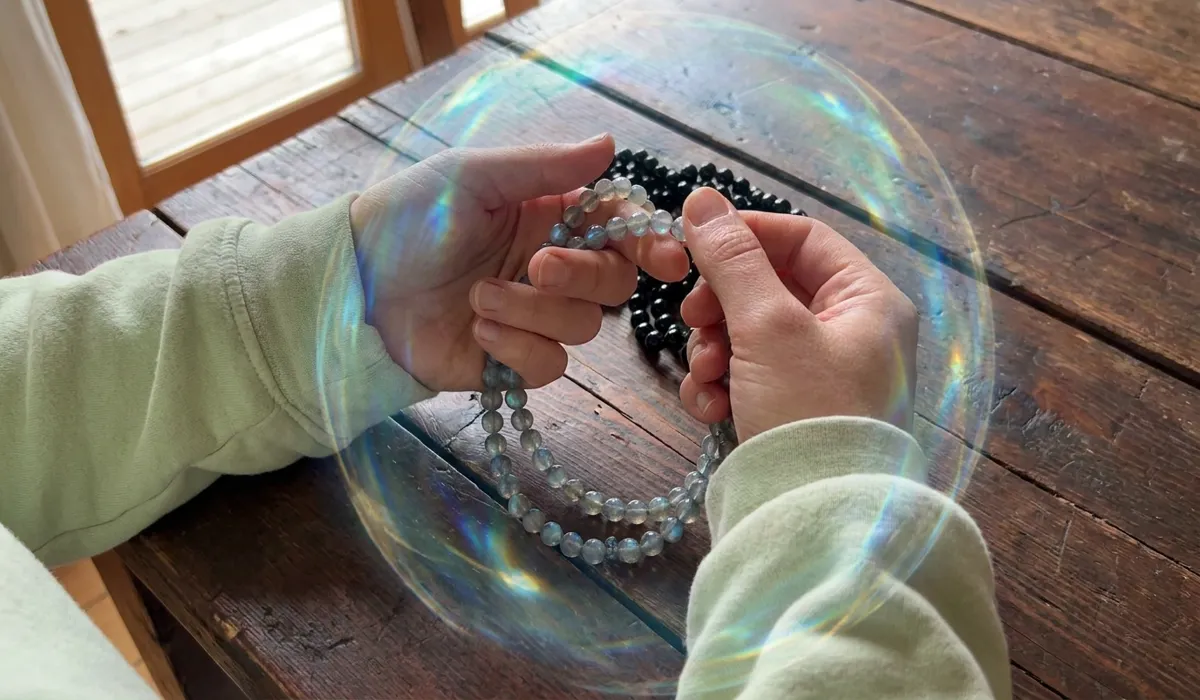 The Spiritual Meaning and Benefits of Labradorite Mala Beads for Meditation 2 - Buddha Bodhis Close-up of hands using Labradorite prayer beads for meditation, illustrating energy shielding and intuitive protection.